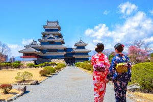 Two geishas wearing traditional japanese kimono among Matsumoto Castle is one of the most complete and beautiful among Japan's original castles