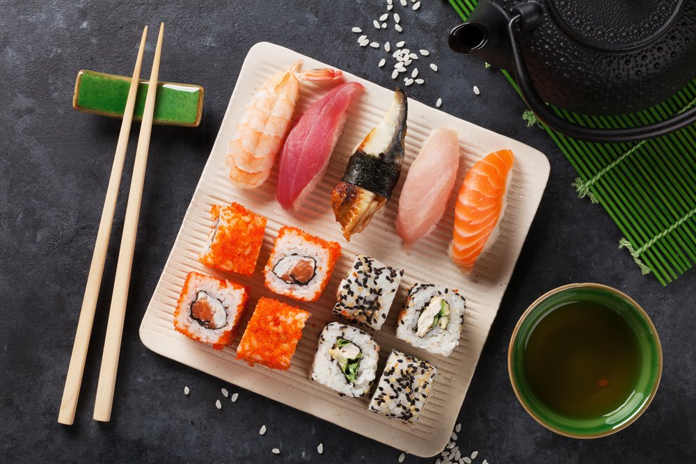 Set of sushi, maki and green tea on stone table