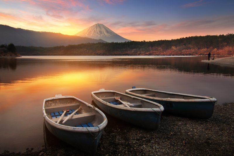 Beautiful scenery during sunrise of Lake Saiko in Japan with the rowboat parked on the waterfront and Mountain Fuji background. Travel and Attraction Concept