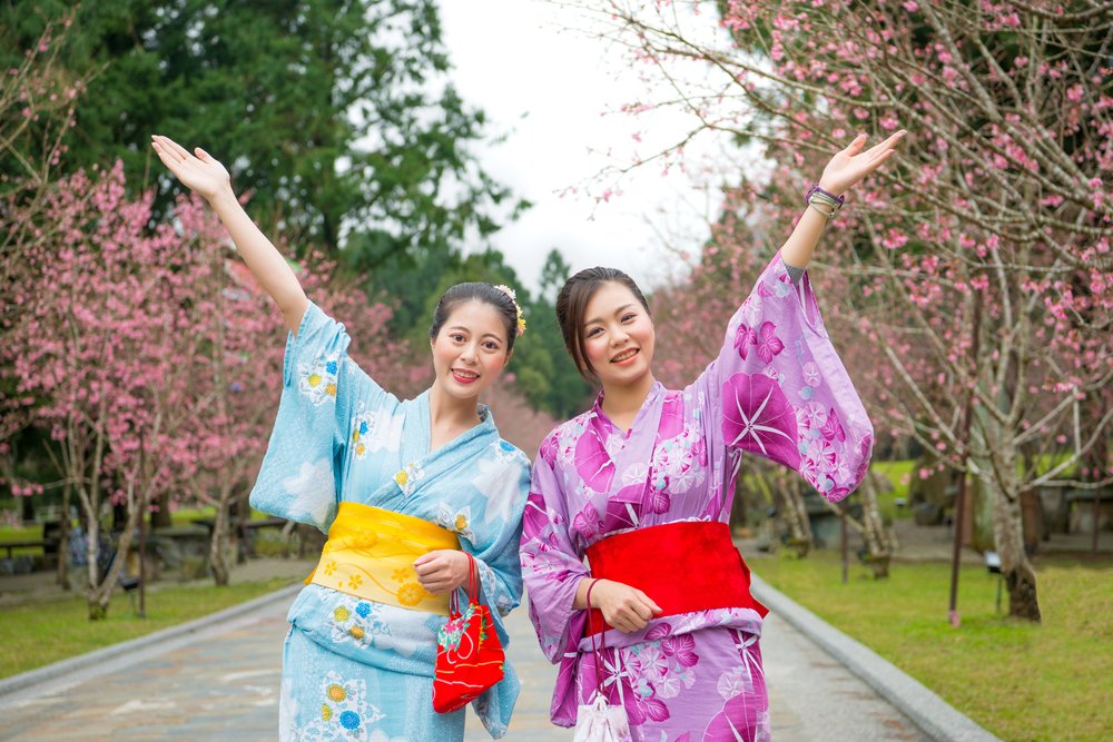 Happy freedom two women open arms with cherry-blossom sanctuary outdoors. Carefree japanese girls sightseeing sakura and dress beauty kimono during april vacation in japan.