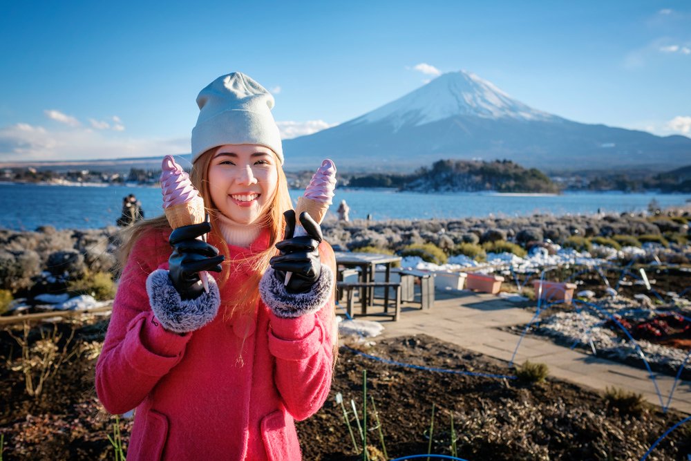 beautiful smile asian girl holding blueberry soft serve ice cream cone with mount fuji