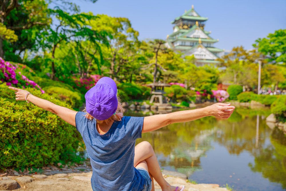 tourist enjoys in front of Osaka Castle surrounded by spring blooms. Freedom and asia travel concept. Defocused background. Osaka Castle is one of the most famous landmarks in Japan and Osaka